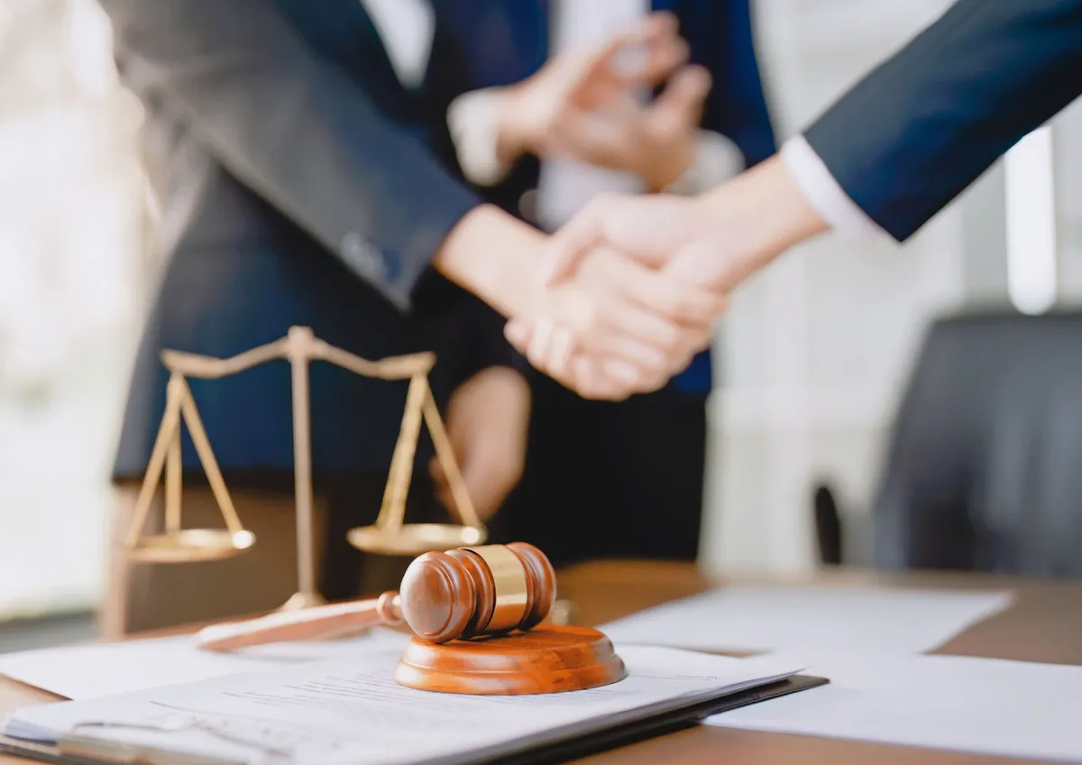 A professional handshake over a desk with legal documents